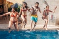 Group of happy friends holding hands and jumping in pool. Young diverse culture people having fun in vacation. Holiday and Royalty Free Stock Photo