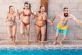 Group of happy friends holding hands and jumping in pool. Young diverse culture people having fun in vacation. Holiday and Royalty Free Stock Photo