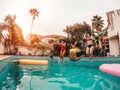 Group of happy friends jumping in pool at sunset time - Crazy young people having fun making party in exclusive tropical house Royalty Free Stock Photo