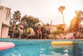 Group of happy friends jumping in pool at sunset time - Millennial young people having fun making party in exclusive resort Royalty Free Stock Photo