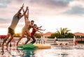 Group of happy friends jumping in pool at sunset time - Millennial young people having fun making party in exclusive resort Royalty Free Stock Photo