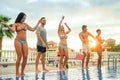 Group of happy friends making a pool party at sunset - Young people having fun dancing next to the pool Royalty Free Stock Photo