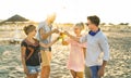 Group of happy friends millennial having fun at beach party drinking fancy cocktails at sunset - Summer joy and friendship