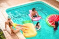 Group of happy friends relaxing in swimming pool - Young people having fun floating on air lilo during summer tropical vacation Royalty Free Stock Photo