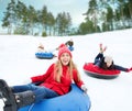 Group of happy friends sliding down on snow tubes