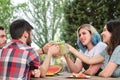 Group of happy friends toasting, having fun, drinking and eating fruit in a park Royalty Free Stock Photo