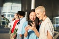 Group of happy friends using the mobile in the street. Young smiling people sharing with cell phone outdoors. Royalty Free Stock Photo