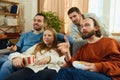 Group of happy, funny people eating snacks during watching favorite TV show, football match sitting on coach at home. Royalty Free Stock Photo