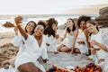 Group of happy group of ladies having fun and drinking wine on beach, taking selfie photo at the hen party on coastline Royalty Free Stock Photo