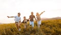 Group of happy joyful school kids boys and girls running with holding hands in field on sunny day Royalty Free Stock Photo