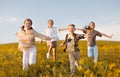 Group of happy joyful school kids boys and girls running with outstretched arms in field on sunny day Royalty Free Stock Photo