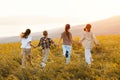 Group of happy joyful school kids boys and girls running with their backs in field on sunny day Royalty Free Stock Photo