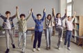 Group of happy junior school students standing with their hands raised in classroom Royalty Free Stock Photo