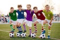 Group of happy junior soccer boys in colorful jersey uniforms. Five joyful kids with soccer football balls smiling Royalty Free Stock Photo