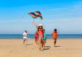 Group of happy kids run with kite on the beach