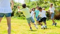 Group of happy kids are running and playing football in park Royalty Free Stock Photo