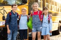 Group of happy kids standing by school bus, embracing and smiling Royalty Free Stock Photo