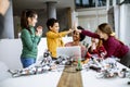 Happy kids with their African American female science teacher with laptop programming electric toys and robots at robotics