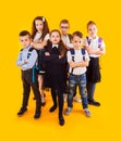 Group of happy kids in uniform with school bags hugging and looking to camera over yellow background Royalty Free Stock Photo