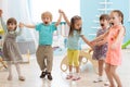 Group of happy kindergarten kids jumping raising hands while having fun in entertainment center