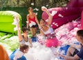 Group of happy men and women swimming in foam pool in adventure park Royalty Free Stock Photo