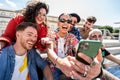 Group of happy multiracial friends using smartphone outdoors, watching social media and laughing. Fashionable people making a Royalty Free Stock Photo