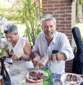 Group of happy people is eating meat outdoors