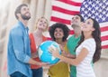 Group of happy people holding globe against American flag and looking up Royalty Free Stock Photo