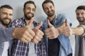 Group of happy positive young men standing together and showing thumbs up gesture Royalty Free Stock Photo