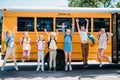 group of happy pupils jumping in front of school bus and looking Royalty Free Stock Photo