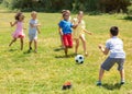 Group of happy schoolchildren playing football together