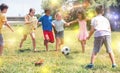 Group of happy schoolchildren playing football together