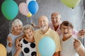 Happy, senior friends holding colorful balloons while posing for a photo at a party Royalty Free Stock Photo