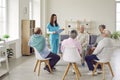 Group of happy senior people at retirement home having discussion with young nurse Royalty Free Stock Photo