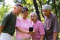 Group of happy Senior Retirement Using Smartphone and laughing outdoors at the park after a workout and spending time together, Royalty Free Stock Photo