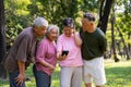 Group of happy Senior Retirement Using Smartphone and laughing outdoors at the park after a workout and spending time together, Royalty Free Stock Photo