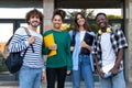 Group of happy and smiling multiracial college students standing in front of university building looking at camera. Royalty Free Stock Photo