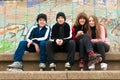 Group of happy teenagers sitting on the street in roller skates