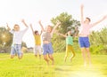 Happy tweenagers jumping on green lawn on summer day