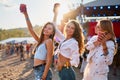 Group of happy women celebrating at a beach music festival, sunlit scene with raised drinks, friends dancing, enjoying