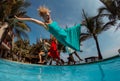 Group of happy women jumping in pool party at sunset - Young people having fun in tropical vacation - Holiday, youth lifestyle