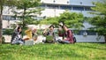 A group of happy young Asian-diverse college students are sitting on the grass in the park together Royalty Free Stock Photo