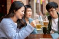 Group of happy young Asian friends are enjoying drinking beers and talking at a bar together