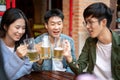 Group of happy young Asian friends are enjoying drinking beers and talking at a bar together