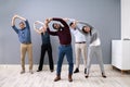 Businesspeople Doing Stretching Exercise At Workplace