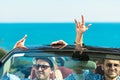 Group of happy young friends in cabriolet with raised hands driving on sunset Royalty Free Stock Photo