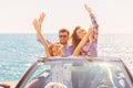 Group of happy young friends in cabriolet with raised hands driving on sunset Royalty Free Stock Photo