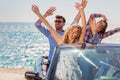 Group of happy young friends in cabriolet with raised hands driving on sunset Royalty Free Stock Photo