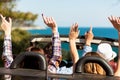 Group of happy young friends in cabriolet with raised hands driving on sunset Royalty Free Stock Photo