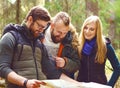 Group of happy, young friends checking a map in forest. Camp, to